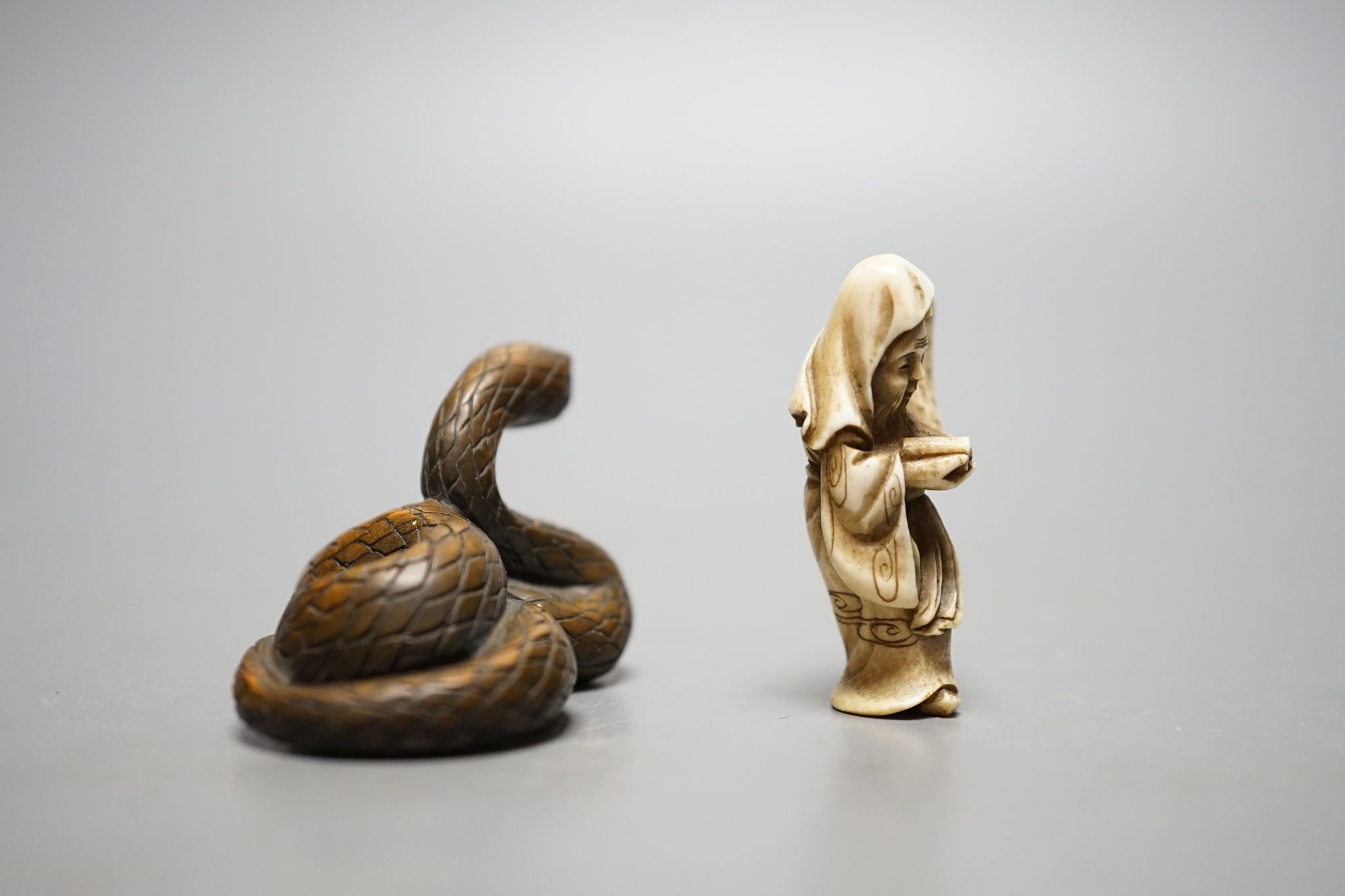 A Japanese ivory figure of a sage and a signed carved wood snake netsuke, 5cm long